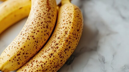 A close-up view of ripe yellow bananas with brown sugar spots, signaling peak sweetness and flavor, resting on a textured marble countertop