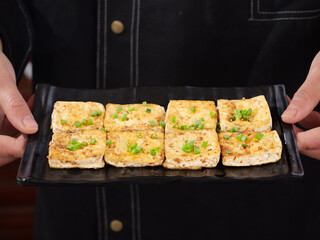 Pan-fried tofu nuggets with green onions on iron plate - Asian vegetarian cuisine