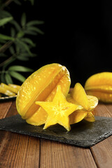 Fresh Ripe Yellow Star Fruit Carambola Slices on Slate Board with Tropical Plants