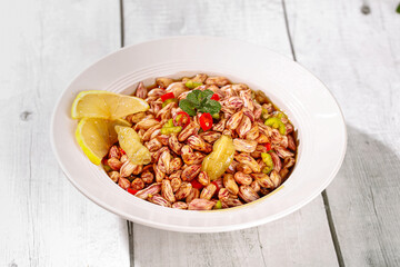 Colorful Boiled Peanuts with Lemon and Peppers in White Bowl on Wooden Background