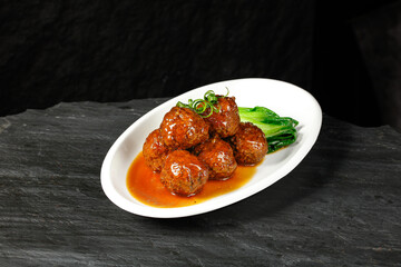 Braised Lion's Head Meatballs Chinese Cuisine Special Banquet Dish with Bok Choy on Dark Slate