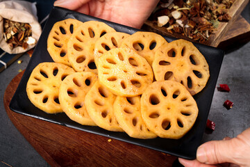 Lotus root slices on black plate with spices for Asian cooking and sautéed dishes