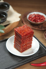 Korean Spicy Dried Squid Jerky Snack with Chili Flakes and Traditional Tea Set on Wooden Table