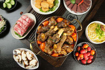 Hot braised lamb stew with vegetables and fresh ingredients on rustic wooden table