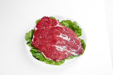 Raw Beef Brisket Cut on White Plate with Fresh Lettuce Garnish