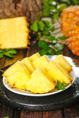 Fresh Sliced Pineapple Chunks on White Plate with Mint Garnish on Rustic Wooden Table