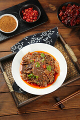 Spicy Sichuan beef tripe in red chili oil sauce - traditional Chinese cuisine with chopsticks and condiments