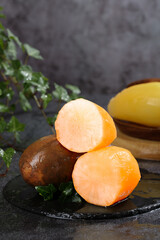 Fresh Sweet Potatoes Halved on Rustic Slate with Herbs and Squash