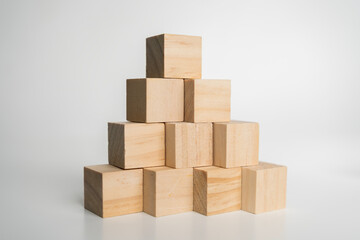 Wooden cubes stacked in pyramid formation on white background symbolizing growth, balance, stability