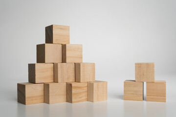 Wooden cubes arranged in pyramid and small stack on white background symbolizing growth and teamwork