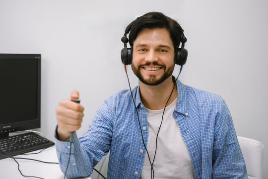 Man wearing headphones and pressing a response button during audiometry hearing test in clinic.