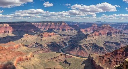 Expansive canyon landscape under a bright blue sky with fluffy white clouds