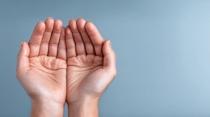 Pair of human hands cupped together with open palms, close up on light blue background, symbolizing care and support