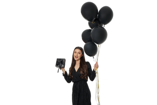 Joyful woman in dark clothes with balloons and a gift, isolated, PNG