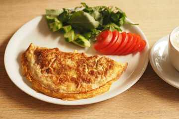Classic omelette with fresh vegetables and coffee on table