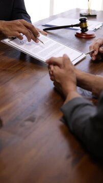 Businessman discussing and signing a contract, negotiating contract terms, reviewing legal document details on wooden office table before collaborative signing and finalizing business agreement.