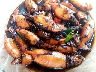 delicious Indonesian-style squid dish cooked with soy sauce, garlic, and spices, served in a glass bowl on a rustic table. Traditional seafood cuisine, rich flavor, and authentic Asian home cooking.