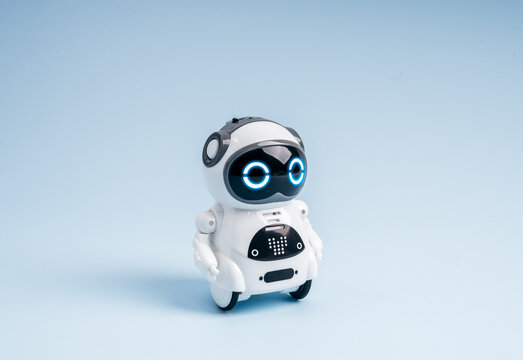 Cute small robot with glowing blue eyes on minimal background. Concept of AI technology, chatbot assistant, AI agent, machine learning, robotics innovation, artificial intelligence, and future tech.