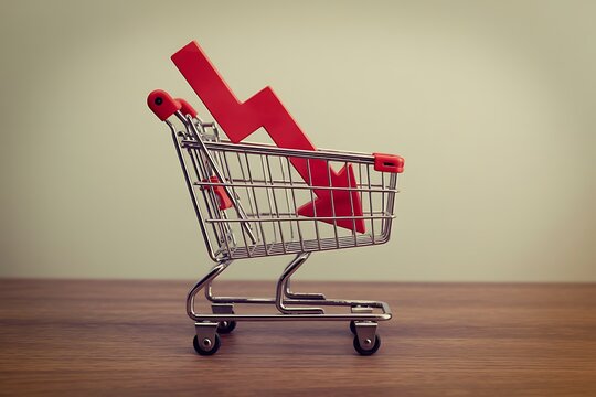 Shopping trolley with red chart falling down on wooden table white wall background copy space. Economic recession crisis, core retail sales decrease, inflation or goods price up concept.
