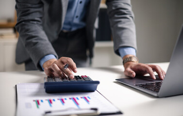 Businessman analyzing digital financial charts and growth trends on laptop, emphasizing the role of technology and data analytics in modern market research and business planning strategies.