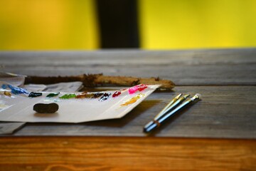 木製のテーブルに置かれた絵の具と筆です。