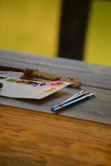 木製のテーブルに置かれた絵の具と筆です。