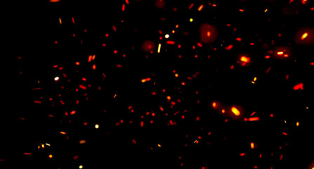 Dark abstract background with glowing orange sparks and embers floating in motion. The fiery particles create an energetic and dramatic atmosphere, ideal for heat, energy, flame, and fire concepts.