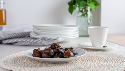Roasted chestnuts served on a white ceramic plate, photographed in a bright minimalist style, winter comfort snack