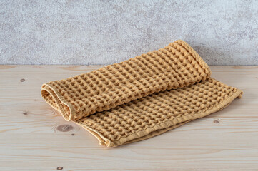 Waffle beige towel on a wooden table.