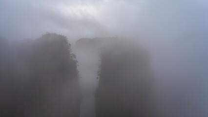 Mystical mountain landscape. The high sheer rock pillars  are shrouded in thick fog. Peaks in the clouds. A foggy morning. Poor visibility. China. Zhangjiajie National Forest Park. Avatar