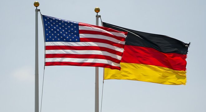 Flags of united states and germany waving against a bright sky background