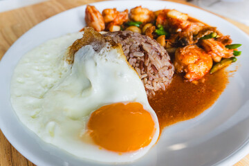Delicious Stir-fried shrimp with chili, fried egg and brown rice as Thai food close-up