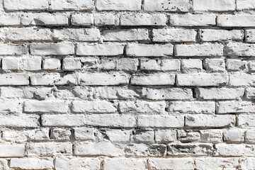Fototapeta premium An old weathered brick wall painted white showcases its rustic texture and character