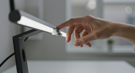 Professional adjusting the brightness of a modern, sleek LED desk lamp with a touch-sensitive control.Concept of workspace technology and smart lighting.