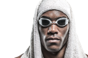 Closeup portrait of a determined black male swimmer wearing goggles and a towel, isolated on transparent background