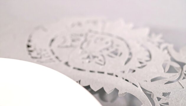 Decorative paper cutout, white, intricate design, on a plate