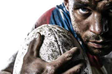 Closeup portrait of a determined rugby player with a muddy face, holding a rugby ball, isolated on transparent background