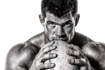 Intense muscular man with beard holding and smelling a rugby ball, isolated on transparent background