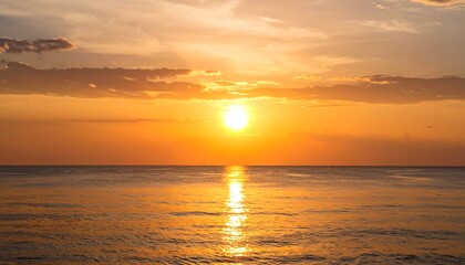 Fototapeta premium Golden sunset over calm ocean waters; sun's reflection visible on the surface