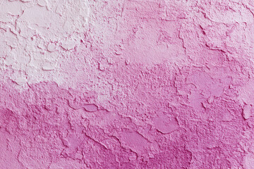 Fototapeta premium An abstract textured background of a rough wall surface with peeling paint in a gradient of pink tones
