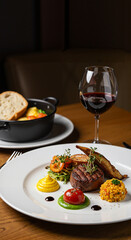 A haute cuisine dish: meat with vegetables and sauce on a white plate, next to a glass of red wine. Here, each piece is not just a meal, but a note in a gastronomic opera.