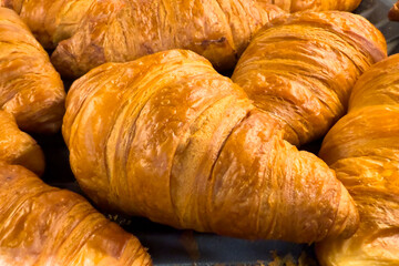 Close-up of fresh golden brown croissants, flaky pastry texture and crispy layers, ideal for bakery, breakfast, pastry shop, and food background concepts.