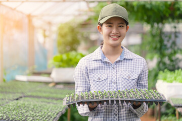 Teenage girl smiles as she holds seedlings in her arms