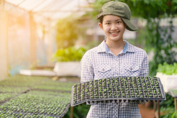 Teenage girl smiles as she holds seedlings in her arms