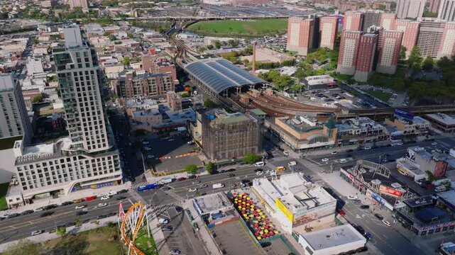 Aerial view of Coney Island Stillwell Avenue subway terminal, residential and commercial buildings, and surrounding city streets with Kaiser Park visible in the distance.