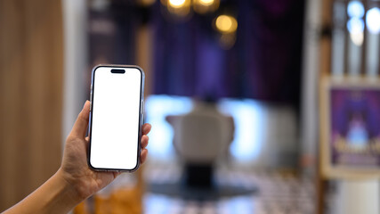 Hand holding smartphone with blank white screen in modern indoor, or app presentation