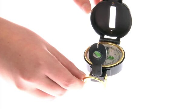 Closeup of hand holding a compass looking for direction. Compass reading and land navigation concept. Tourist compass and magnetic declination calculator. Navigation, searching, exploring concept.