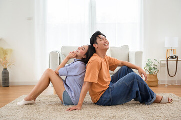 Fototapeta premium Young Couple Enjoys a Cozy Moment Together While Sitting Back to Back in a Stylish Living Room