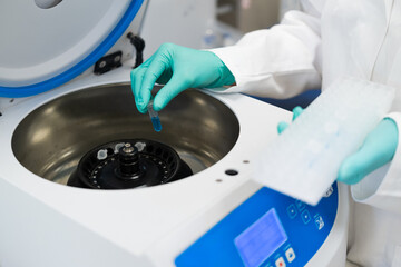 Woman hands in rubber gloves insert test tubes to centrifuge in chemical laboratory 