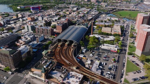 Aerial view of Coney Island Stillwell Avenue subway terminal, residential and commercial buildings, and surrounding city streets with Kaiser Park visible in the distance.